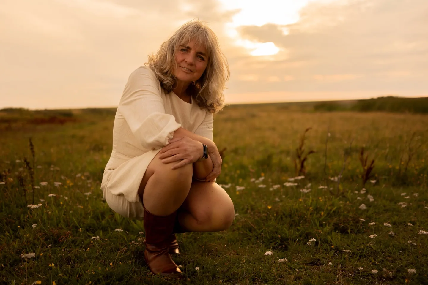 Tineke Hovius buiten in een open landschap bij warm avondlicht.